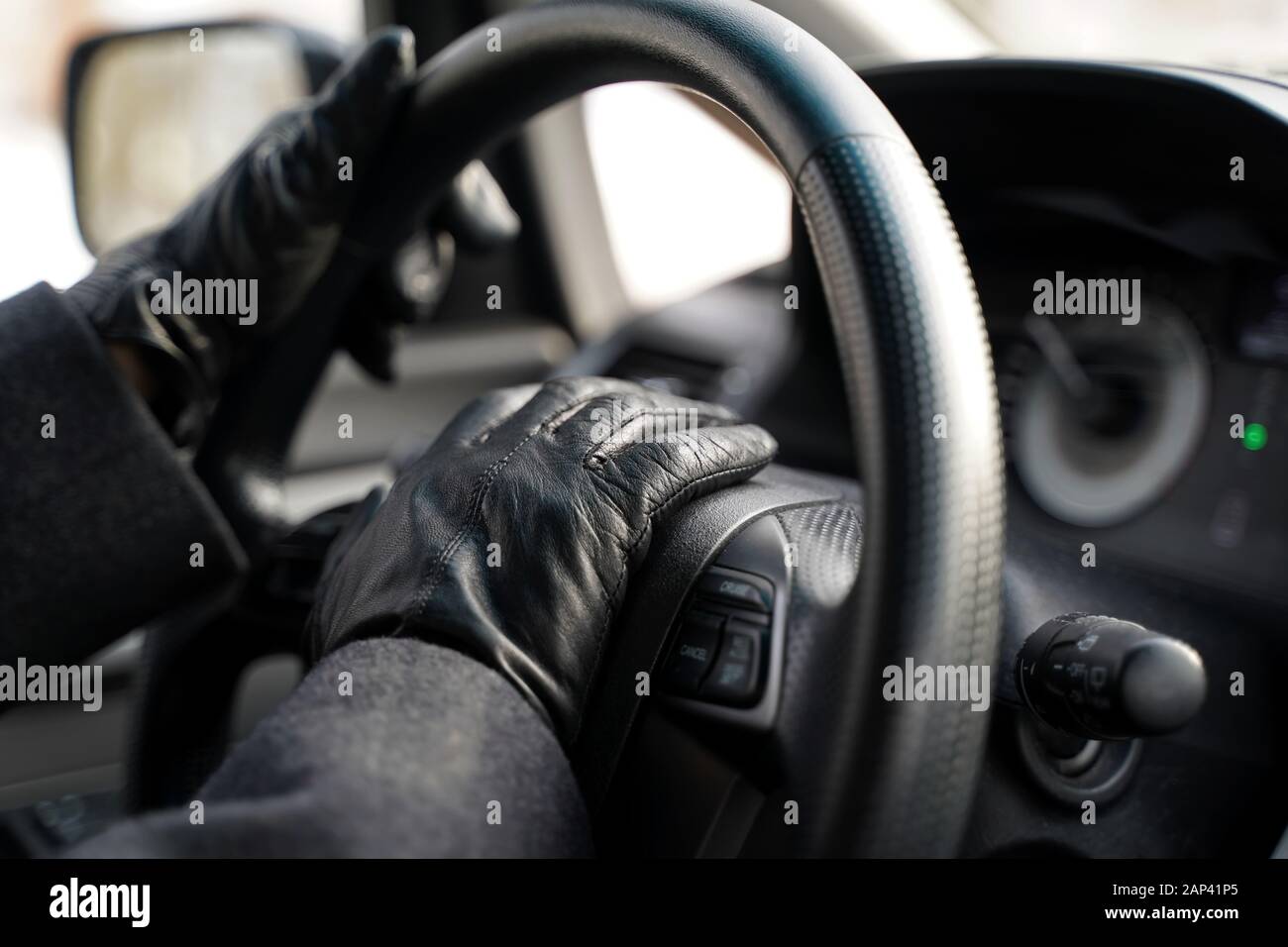 Driving hands in leather gloves blowing horn by pressing down on car`s